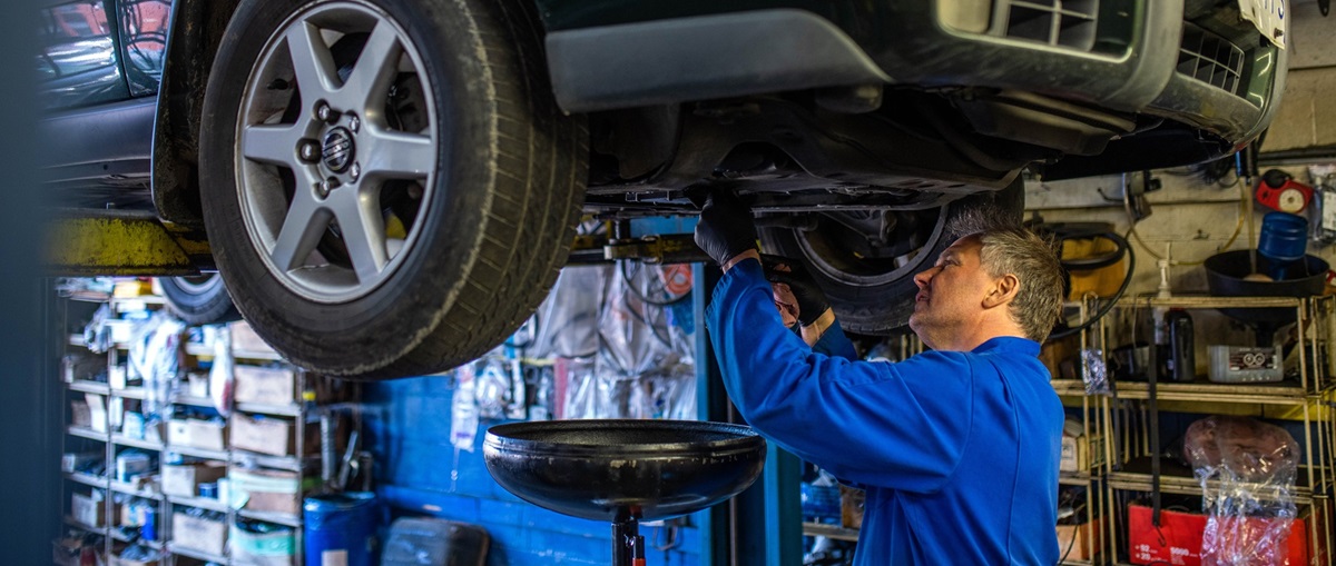 Mature male mechanic working on vehicle on lift