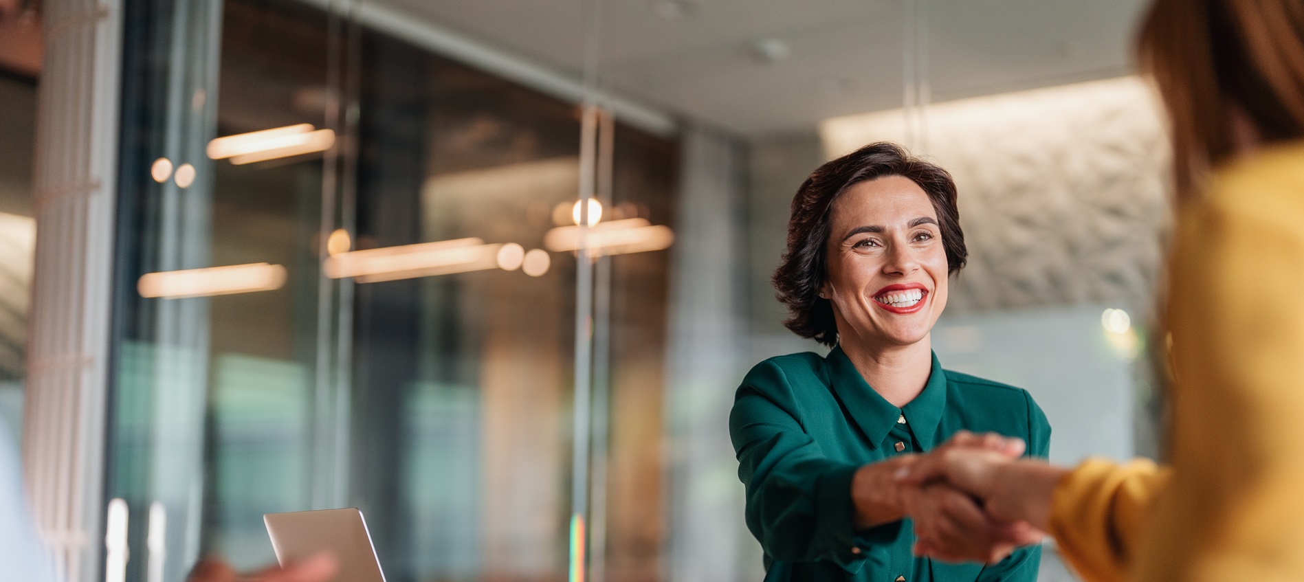 Woman smiling as she shakes another's hand