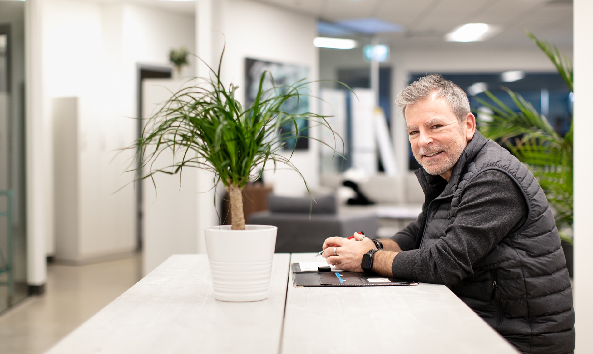 mature male leaning against office counter with his notebook