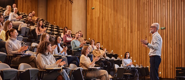 Mature male professor in lecture hall standing in front of student 