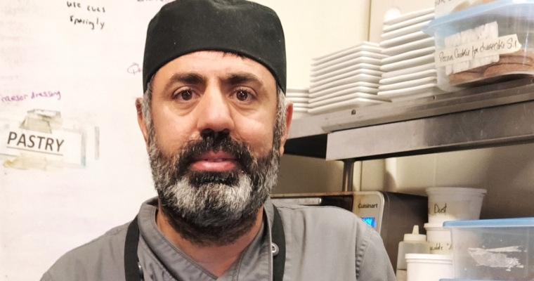 Imam poses in the kitchen at his new job.