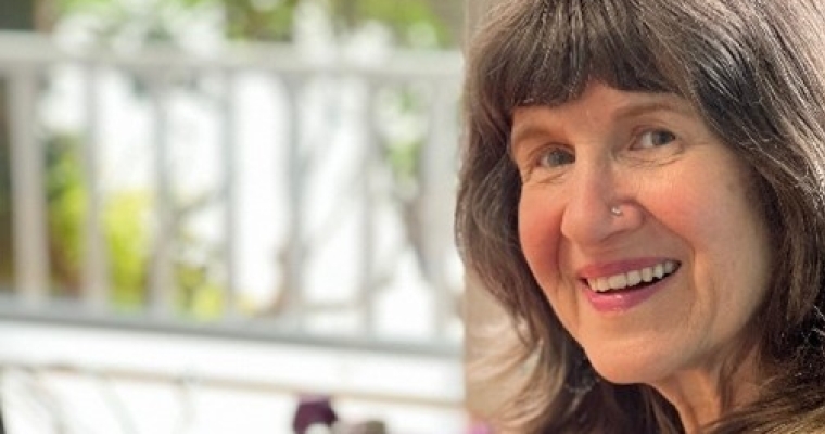 Woman at home office by big window smiles.