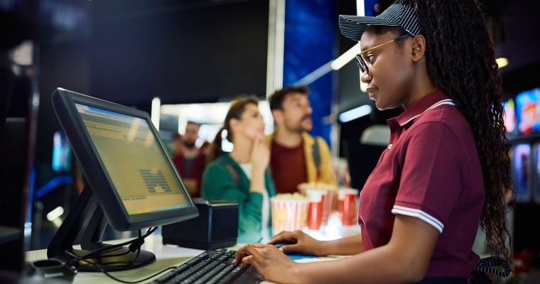 young BIPOC woman selling tickets at a movie theatre