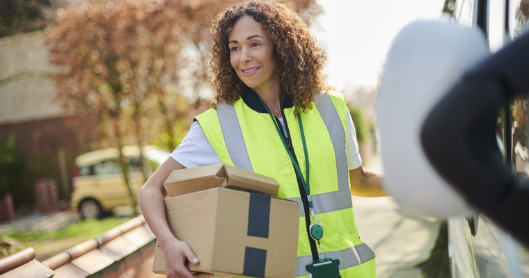 Female courier wearing a safety vest delivering parcels.