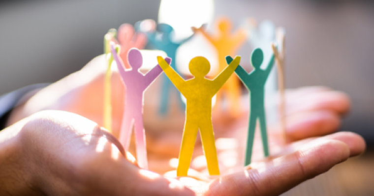Multi-coloured cut-out paper people in a circle with arms raised 