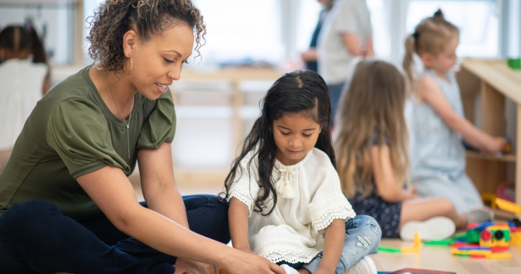 Early childhood educator playing magna tiles with young girl