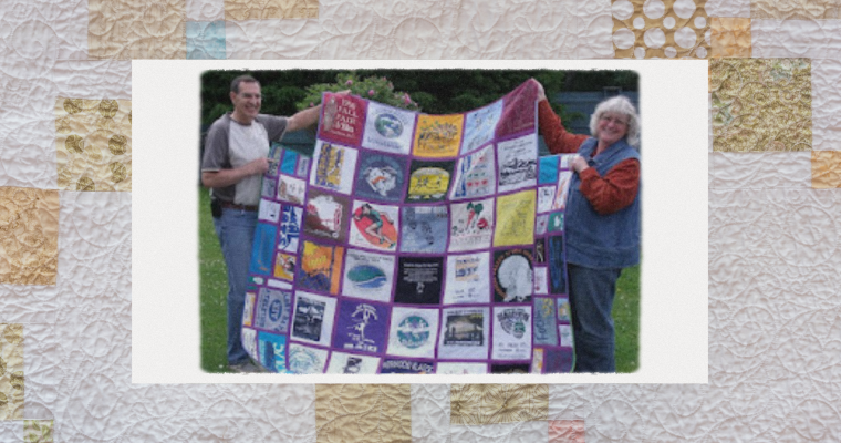 Caroline and a man holding up one of her quilts