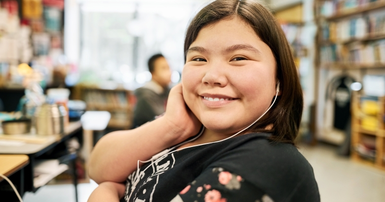 Female Indigenous teenager in classroom with headphones on