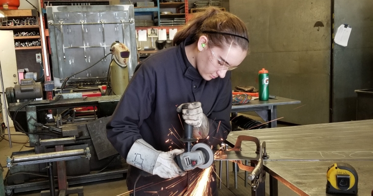 Sara welding in shop wearing protective gear