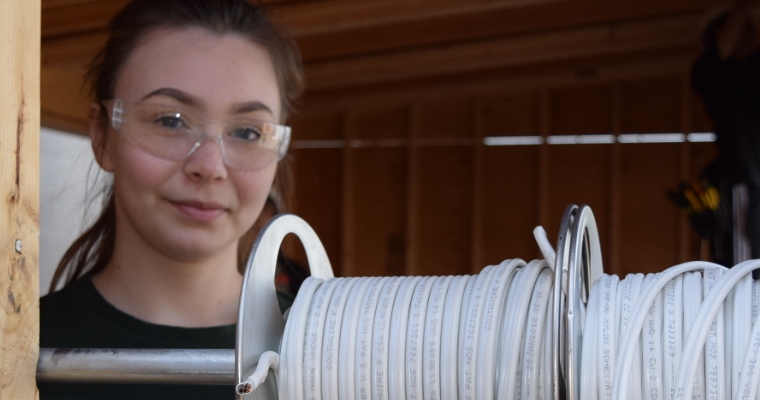 Kendra on the job as an electrician wearing safety glasses