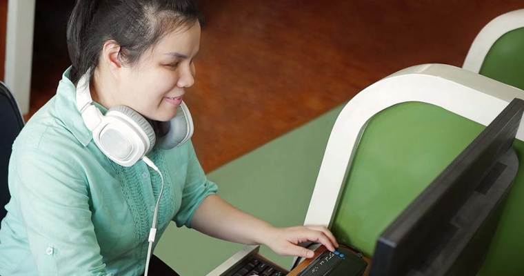 visually-impaired young woman sitting at computer using braille keyboard