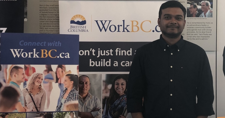 Hasan standing in front of WorkBC banner