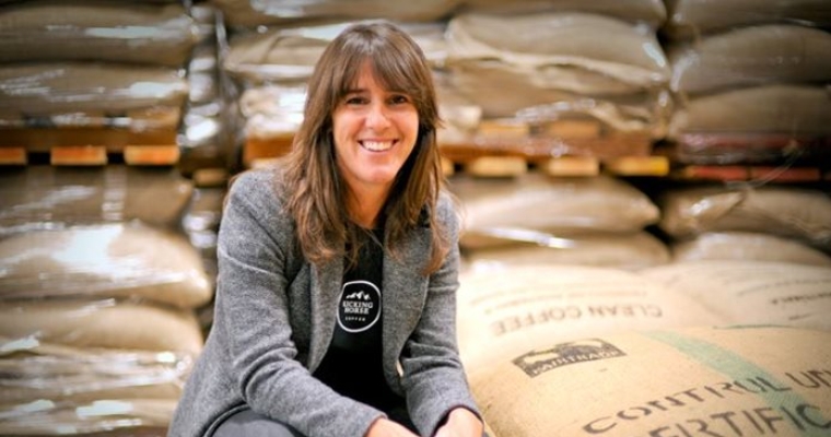 portrait of Elana crouching next to bags of coffee