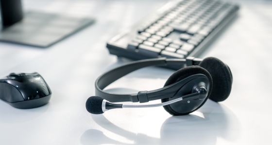 Headphones and keyboard with mouse sit on table top.