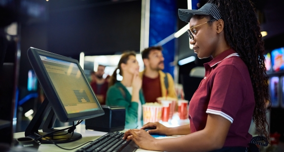 young BIPOC woman selling tickets at a movie theatre