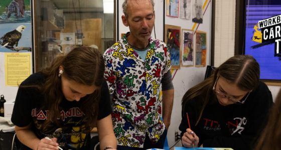 Secondary school art teacher Perry Rath instructing students in his classroom. On the right side of the image is WorkBC's Career Trek logo.