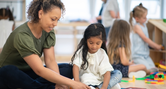 Early childhood educator playing magna tiles with young girl