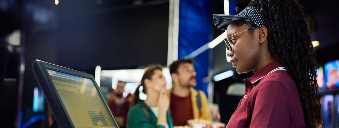 young BIPOC woman selling tickets at a movie theatre