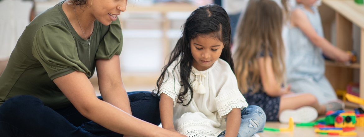 Early childhood educator playing magna tiles with young girl