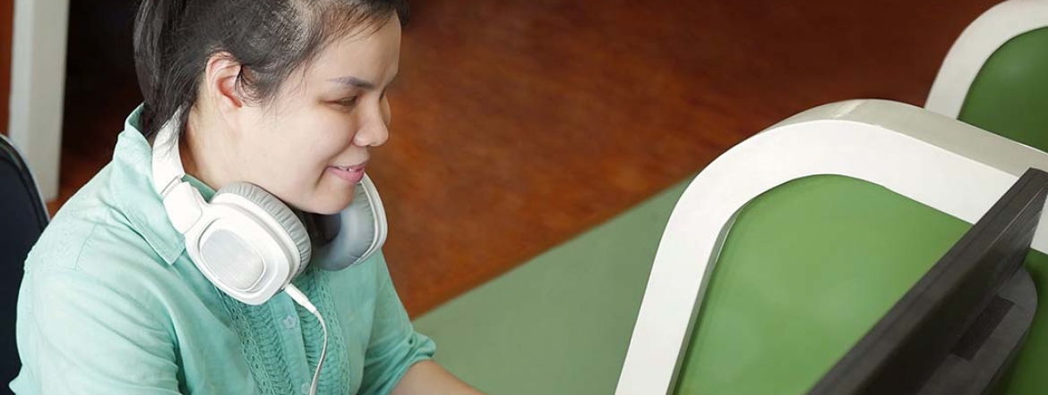 visually-impaired young woman sitting at computer using braille keyboard