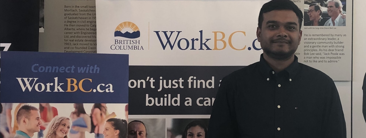 Hasan standing in front of WorkBC banner