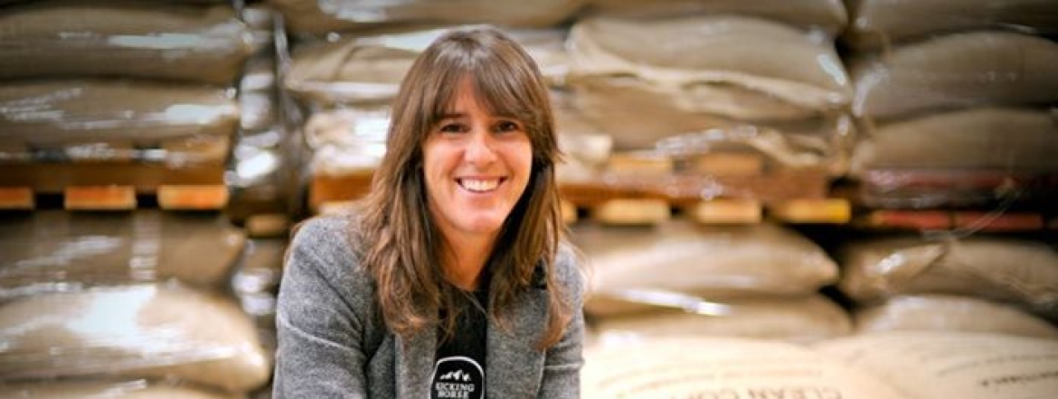 portrait of Elana crouching next to bags of coffee