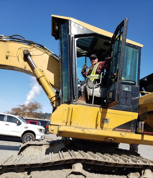 Darryl sits on a construction site inside his heavy equipment.