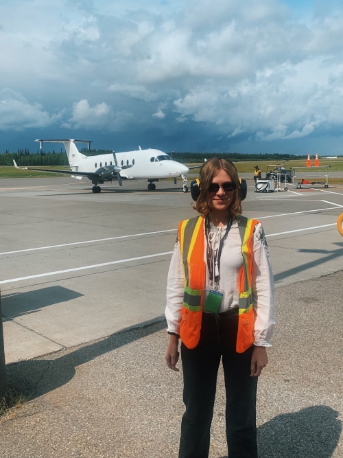 person with reflective gear in front of an airplane