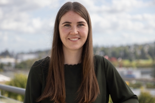 Emily smiling at the camera while standing outdoors on a sunny day.