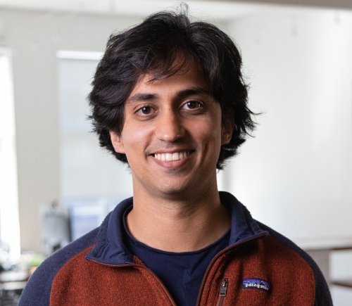 Suro standing in an office smiling at the camera.