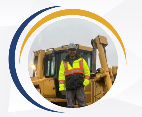 Male construction worker wearing safety equipment next to machinery