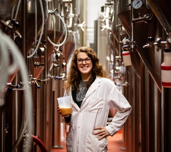 female chemist in lab coat holding a beaker