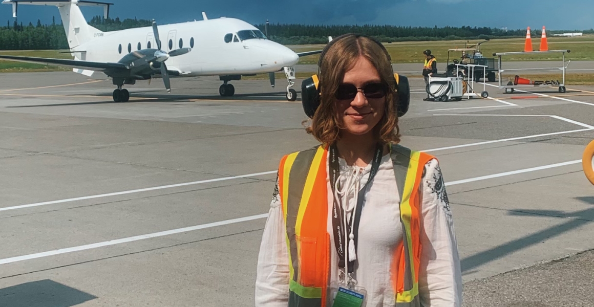person with reflective gear in front of an airplane