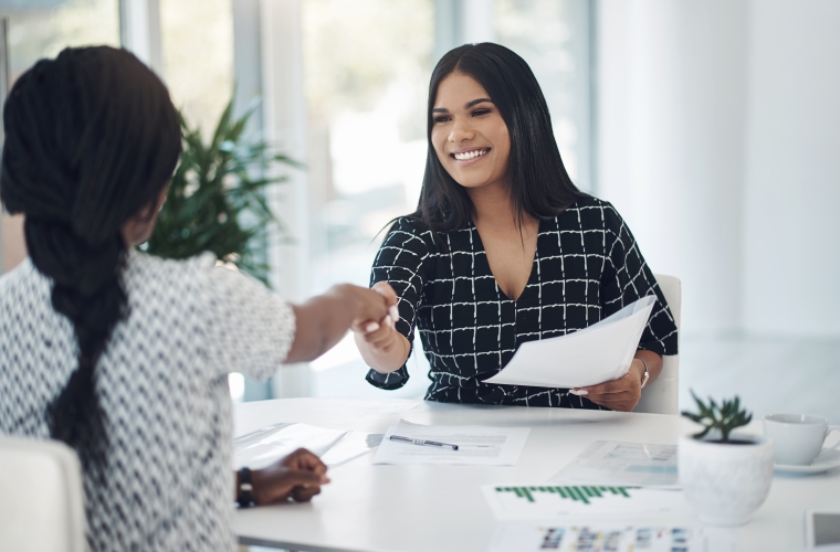 two bipoc women shaking hands in interview