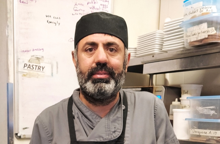 Imam poses in the kitchen at his new job.