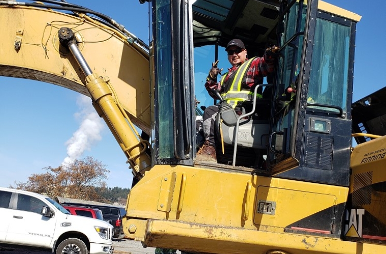 Darryl sits on a construction site inside his heavy equipment.