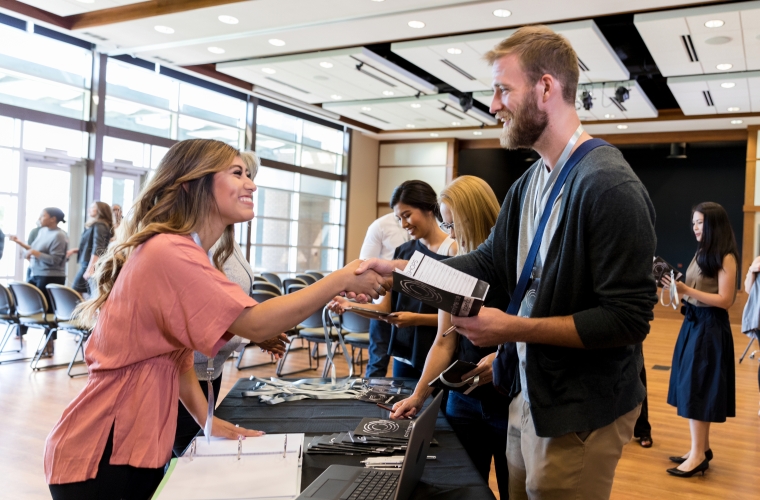 man and woman shaking hands over a career fair table