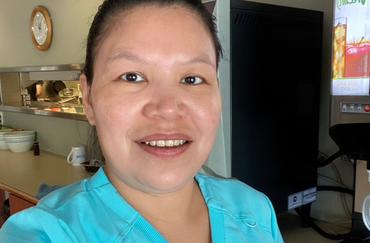 Kristen looks at camera in her work uniform at her new job. Cropped version.