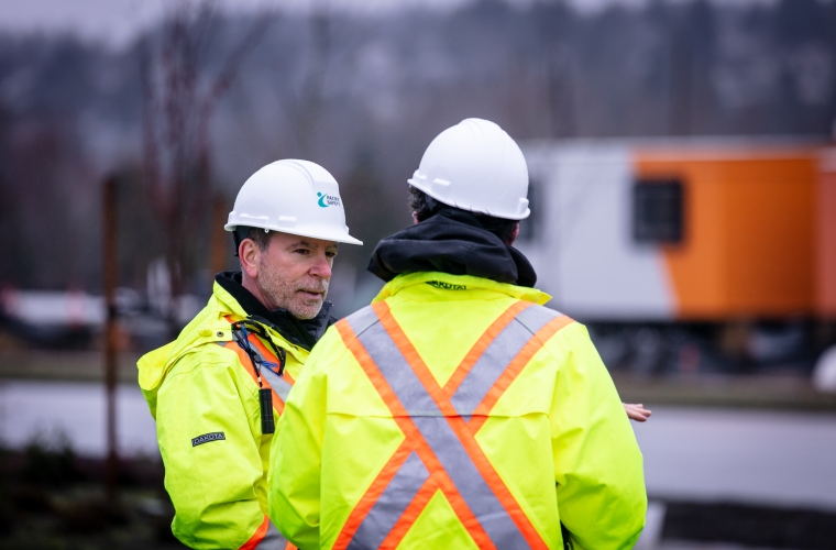 two people talking while wearing yellow safety vests