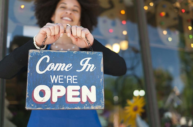 woman holding open sign_outside cafe_landscape_1000x700-sent