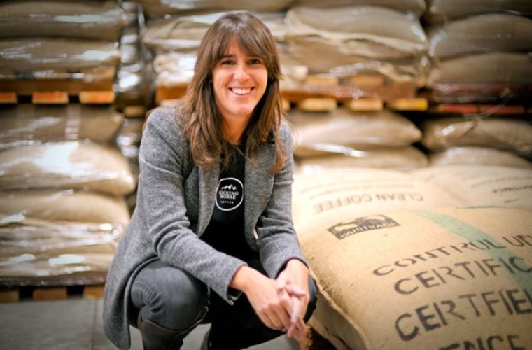 portrait of Elana crouching next to bags of coffee