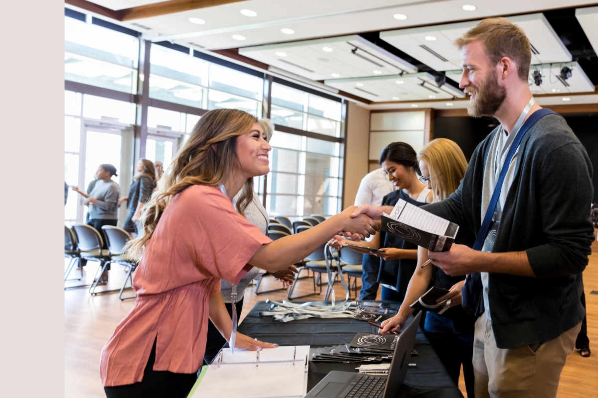 man and woman shaking hands over a table at a career event