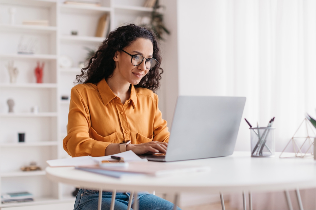 Woman with dark hair and glasses working on laptop