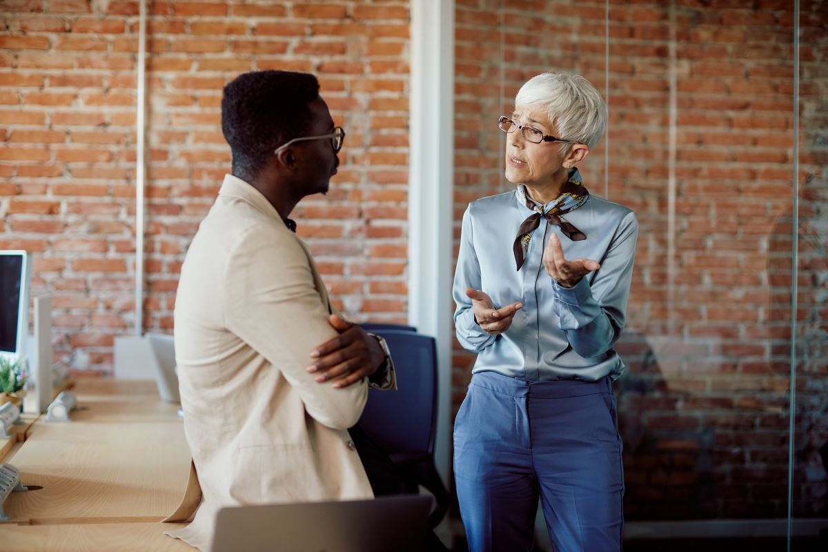Mature woman talking with her black male coworker in the office.