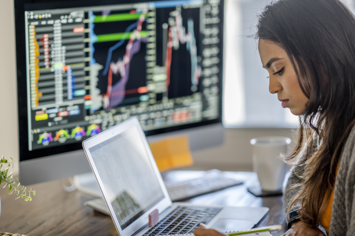Middle Eastern woman tracking and trading stocks on her computer. 