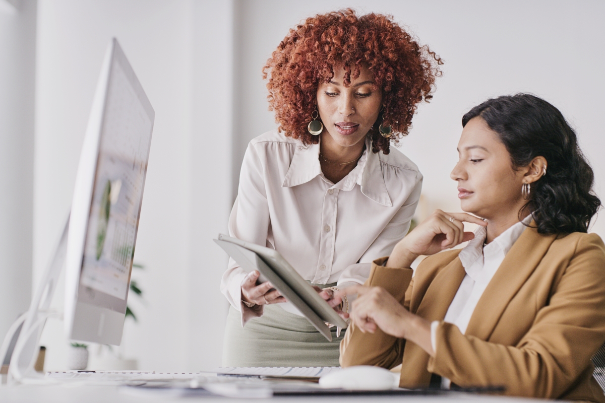 Diverse female colleagues reviewing her manager's schedule on her tablet 