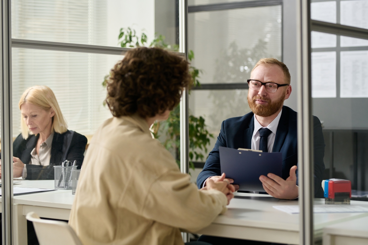 Male consultant talking to woman in cubicle at agency office
