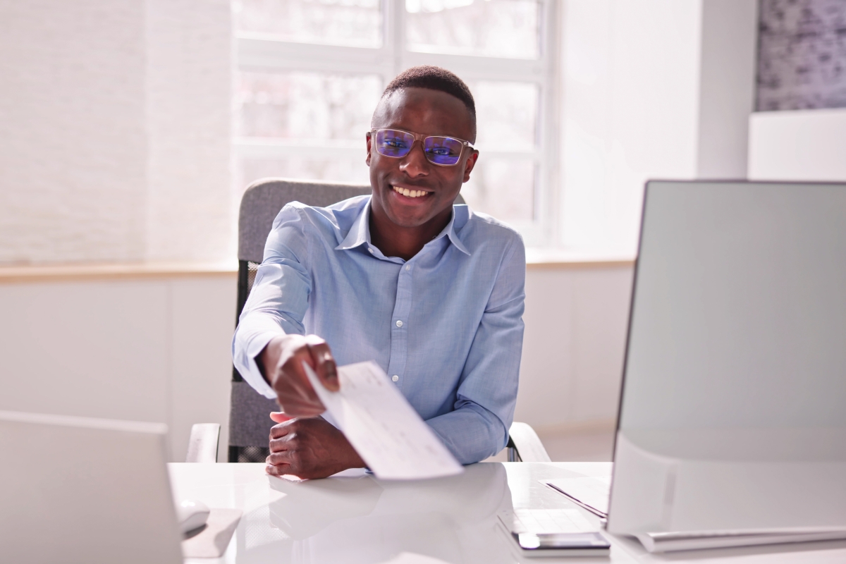 Black male payroll administrator providing a cheque