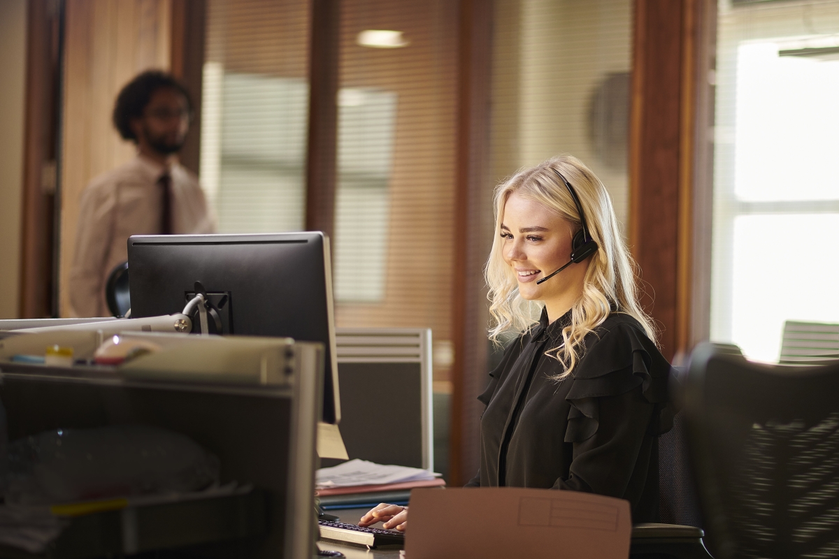Young female paralegal talking with headset while on computer 