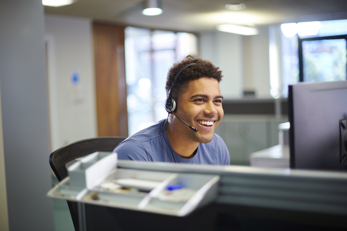male BIPOC receptionist smiling while on a call